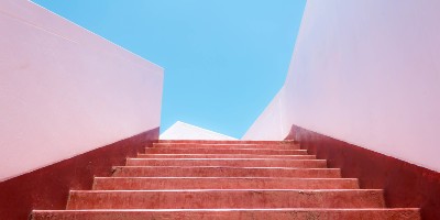 Looking up stairs between pink walls towards blue sky - Language Acquisition