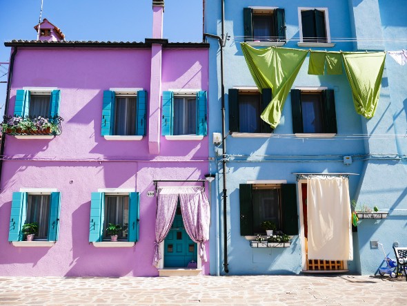 'Summer hues' by Hannah Reynolds. Brightly-painted pink and blue houses with curtains and laundry billowing outside