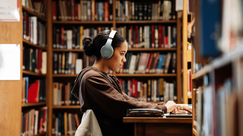 A student using a laptop at a desk in the MMLL Library. 
