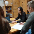 Postgraduate students collaborating on work at a table with a laptop and papers in Clare Hall Library