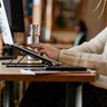 Student typing on a laptop at a library desk.