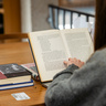 Student reading a book on Chrétien de Troyes in the MMLL Library.