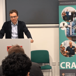 William Selinger stands at a lecture podium in Cambridge
