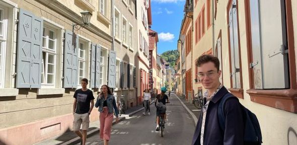 Robbie Spiers Robbie Spiers looks towards camera in a narrow street with Germanic architecture