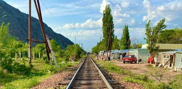'Trackside in Uchuruk' by Barney Crawford. A view along a railway track with buildings and trees either side 'Trackside in Uchuruk' by Barney Crawford. A view along a railway track with buildings and trees eit