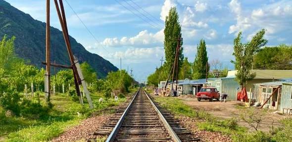 'Trackside in Uchuruk' by Barney Crawford. A view along a railway track with buildings and trees eit